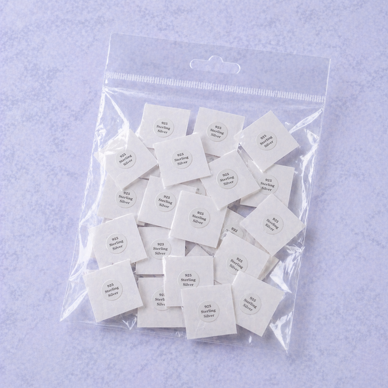 Clear plastic bag filled with white square samples on a light purple background