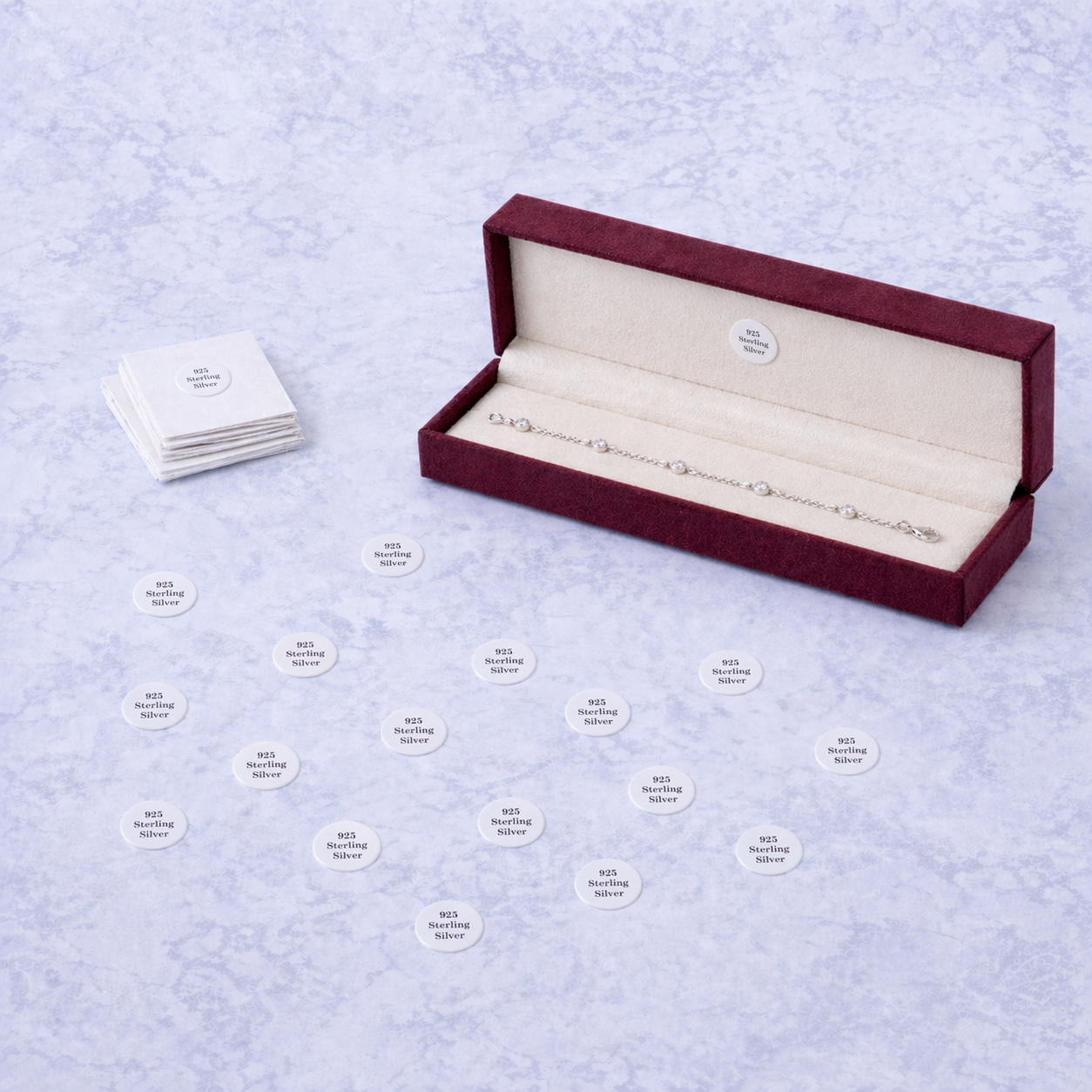 Open jewelry box with a bracelet inside, surrounded by small cards on a light blue textured background